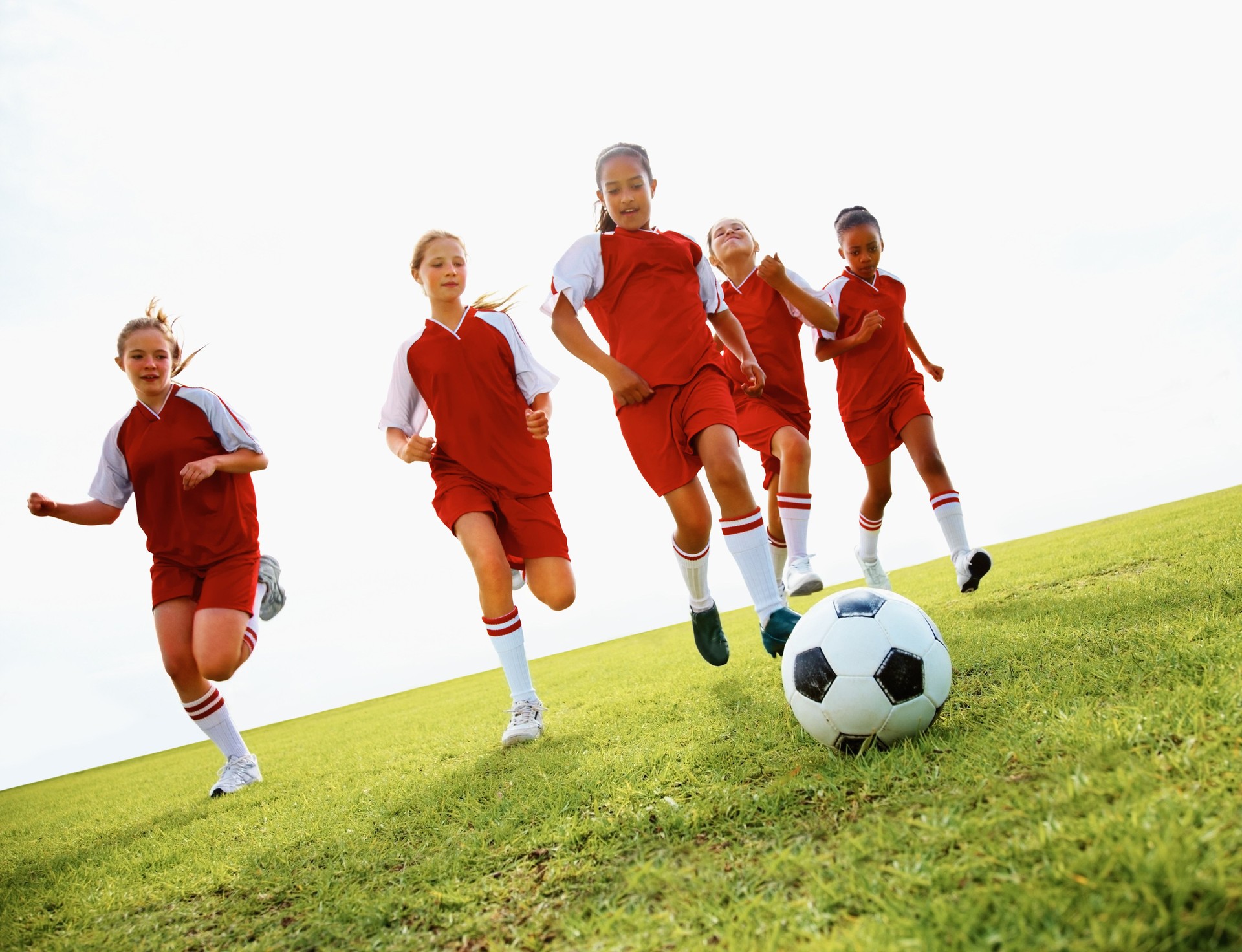 Team of athletic school children playing football in stadium