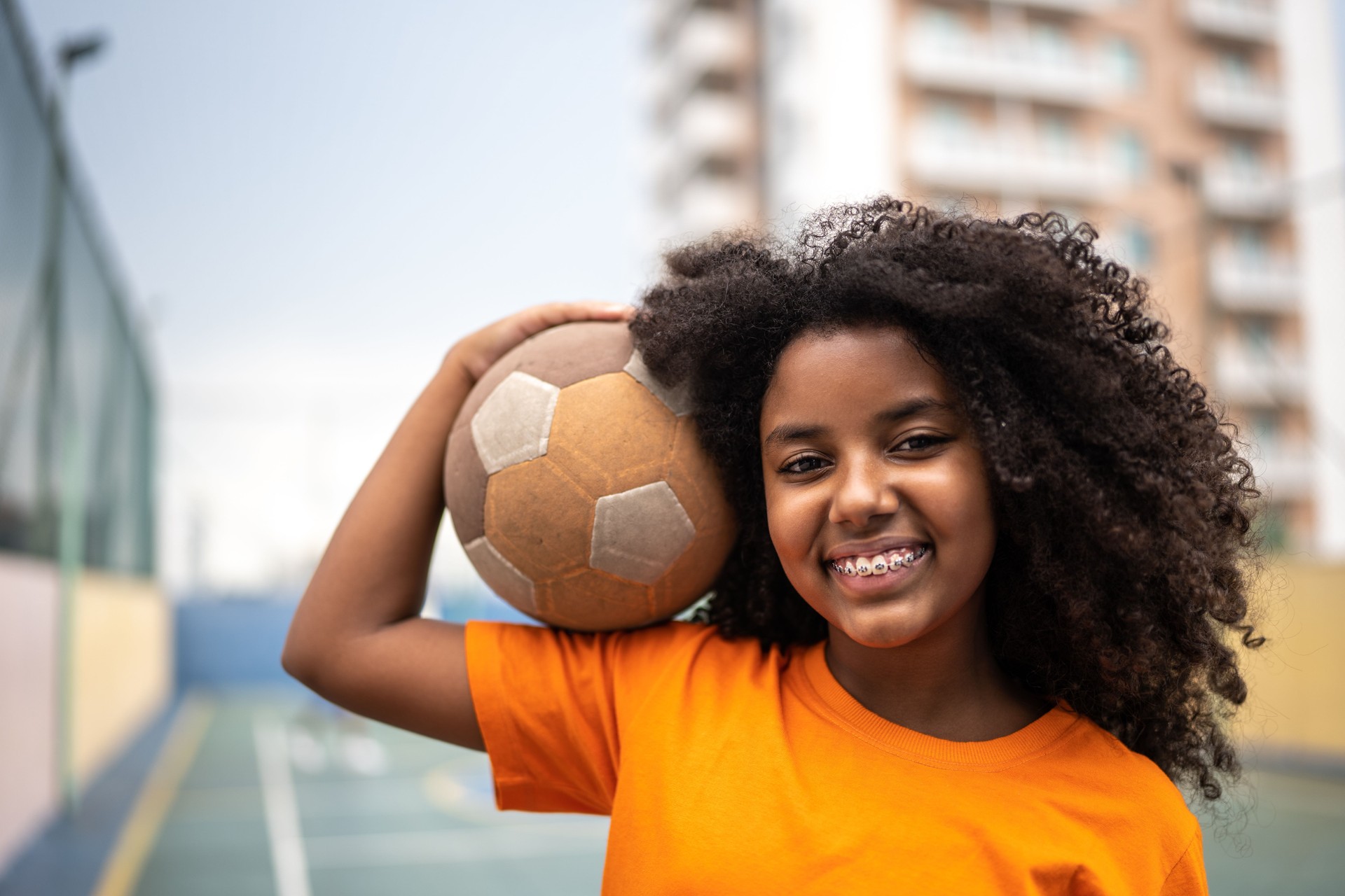 Portrait of a girl holding a ball at a sports court