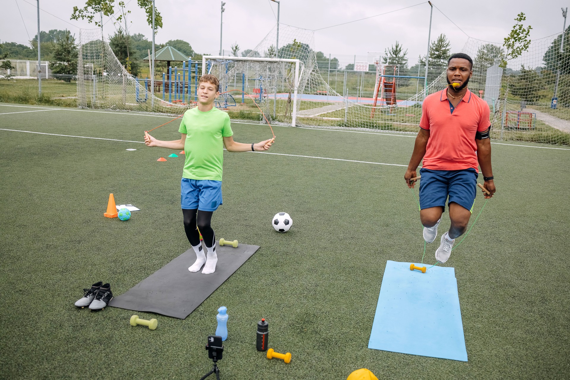 Boy having individual soccer training by the black coach on sport fioeld